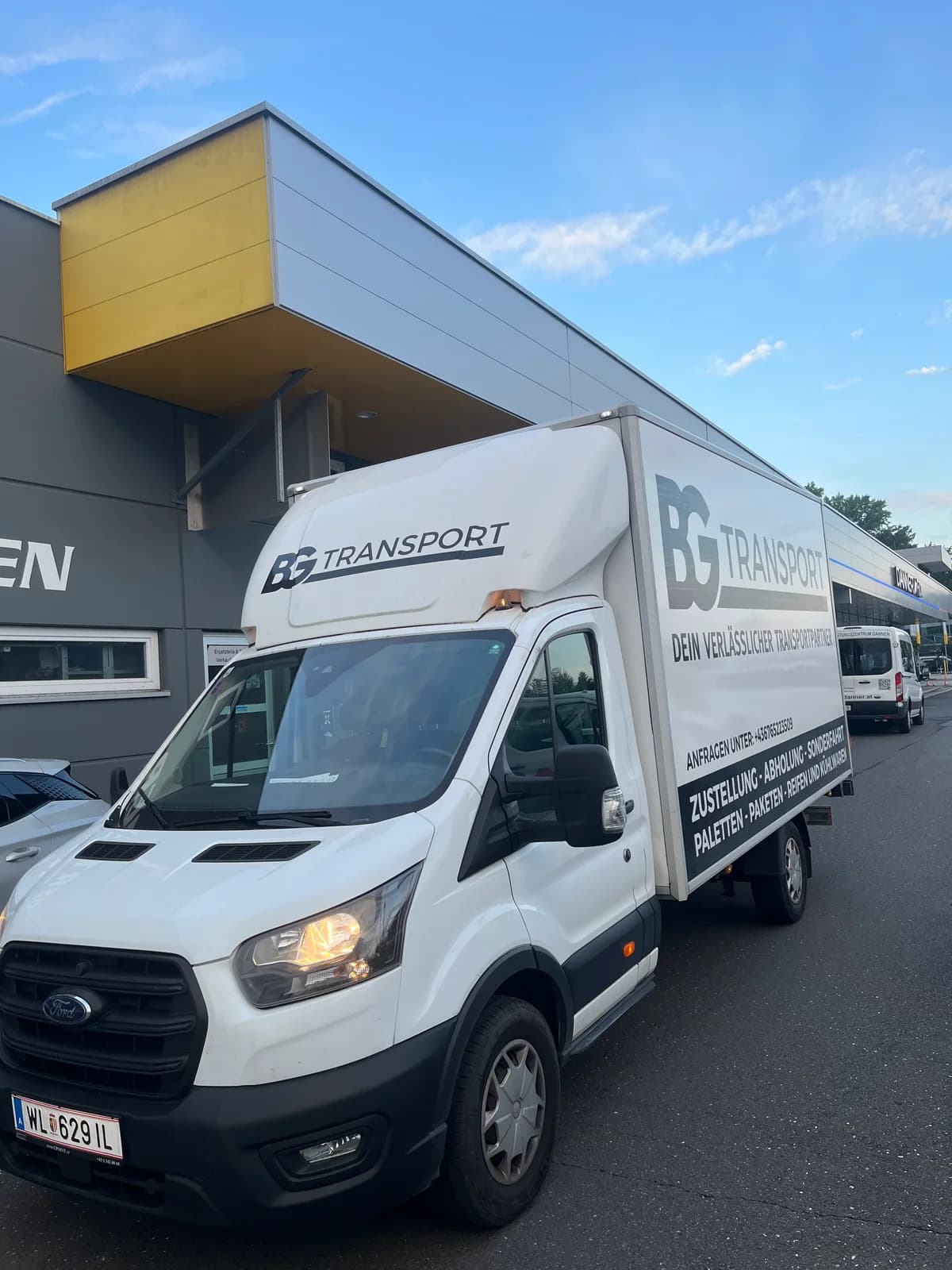 Weißer Koffertransporter mit BG-Transport-Beschriftung